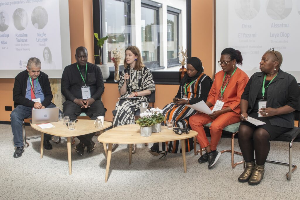 A group of 6 people sitting in a panel formation at a conference. 