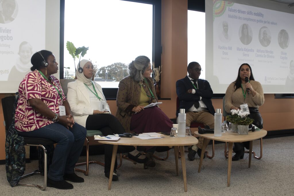 A group of 5 people sitting in a panel formation at a conference. 