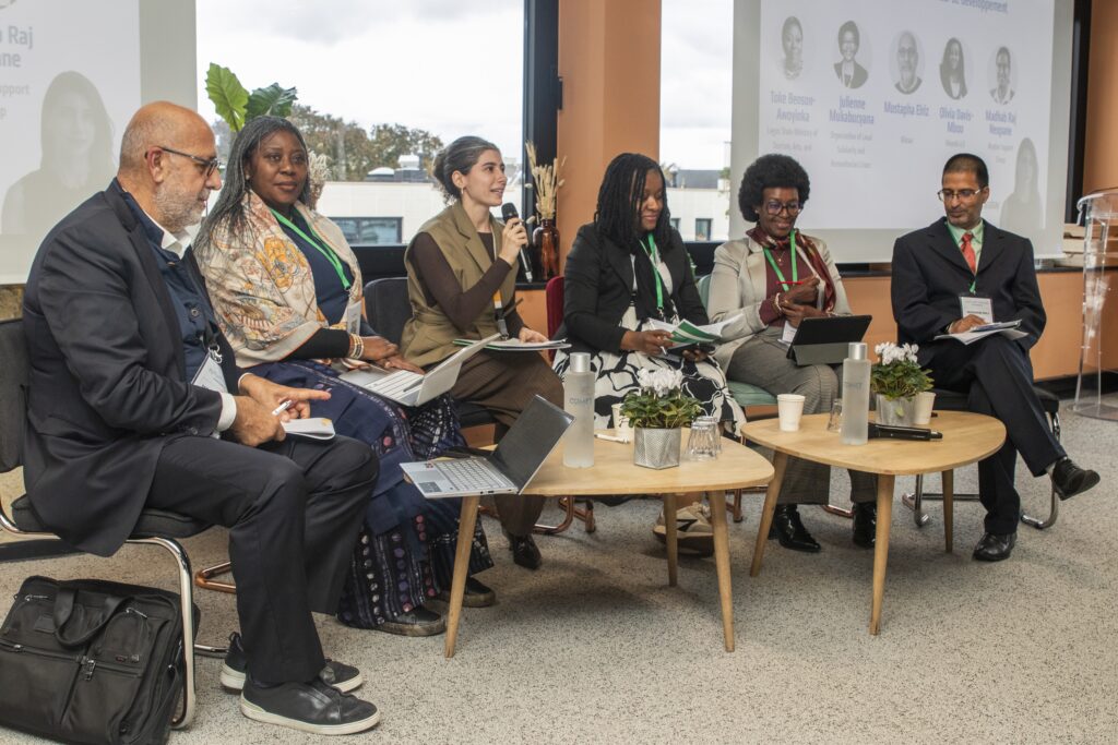 A group of 6 people sitting in a panel formation at a conference. 