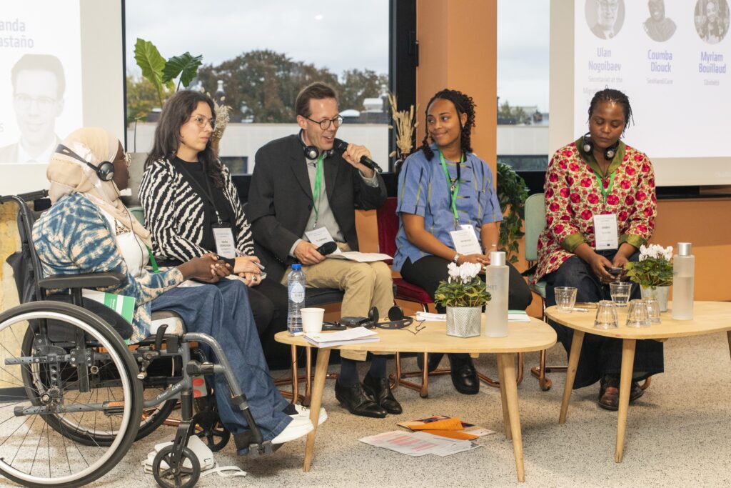A group of 5 people sitting in a panel formation at a conference. 