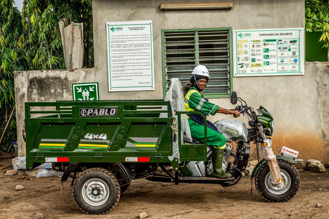 A woman on a bike truck looks at the camera.
