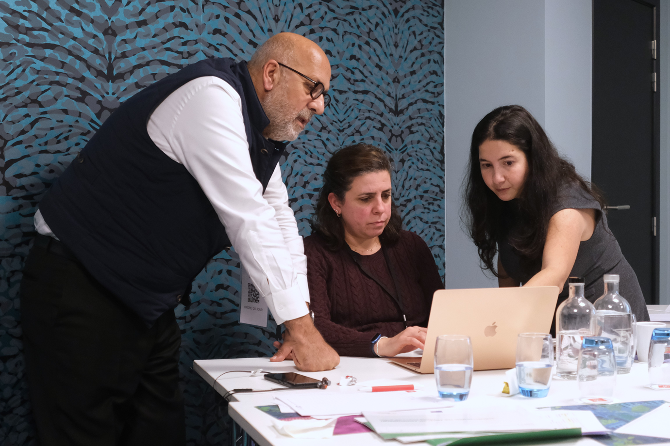Three people standing in front of a laptop pointing at the screen