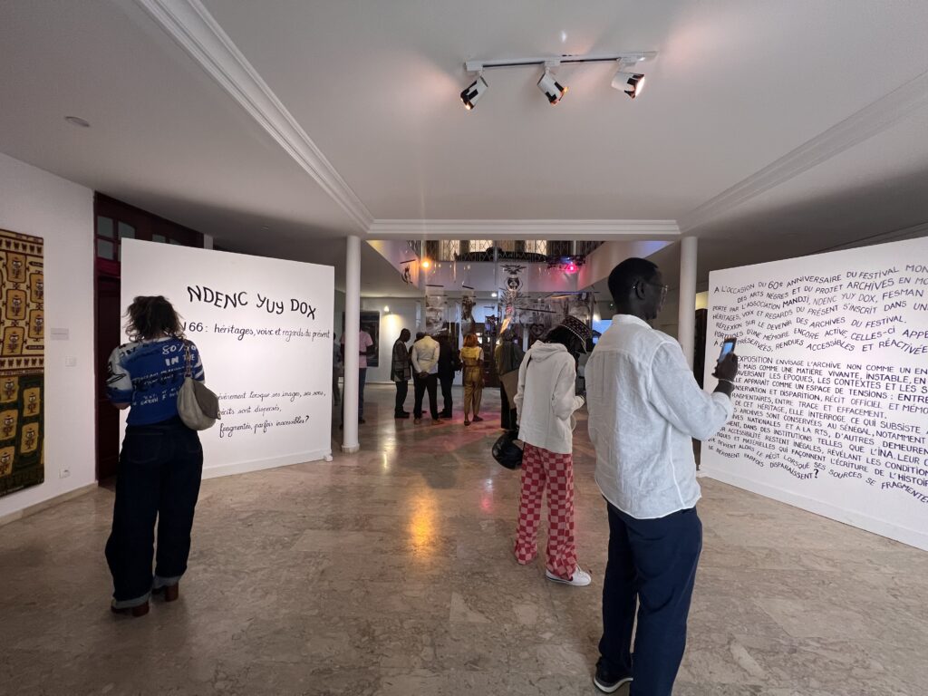 Three people are standing at the entrance of an exhibition taking pictures at the words written on the walls. 